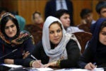 Afghan women taking notes at an event. There is a microphone at their table