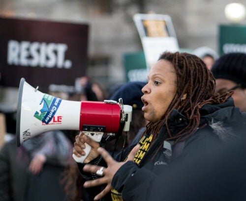 Photo of a woman speaking into a microphone at a march.
