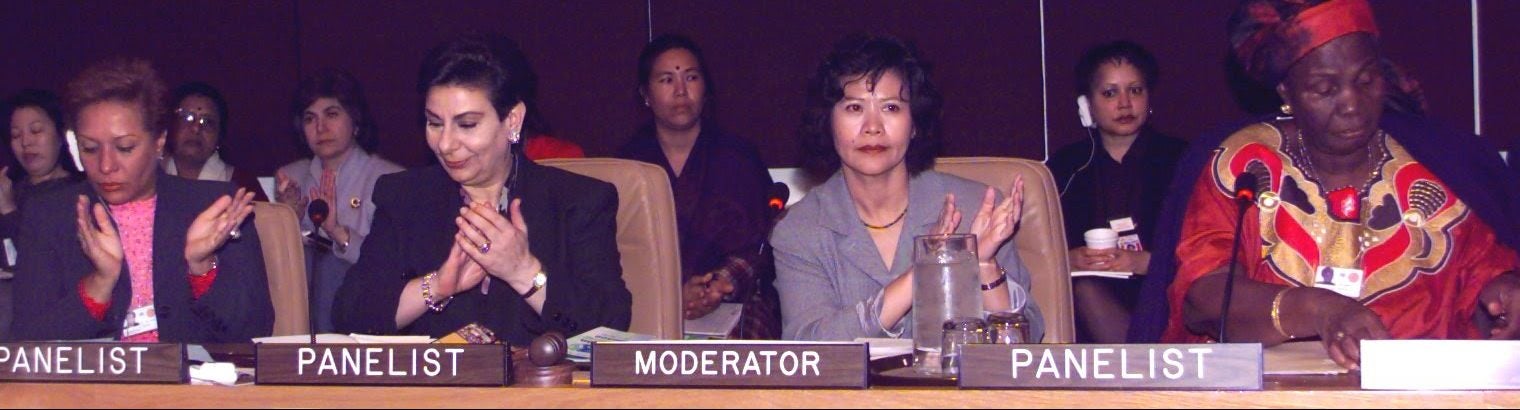 An image of four women sitting on a panel for speakers at a formal negotiation.