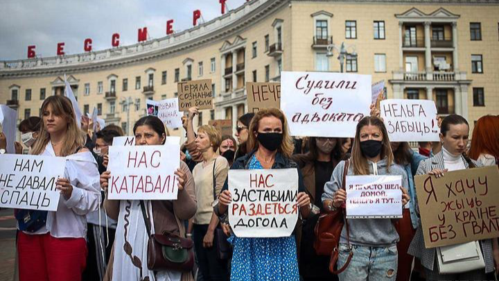 Women in Belarus stand in the streets holding protest signs