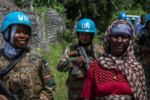 A cropped version of the report cover shows women soldiers wearing United Nations helmets carrying guns and smiling while walking with a local resident.