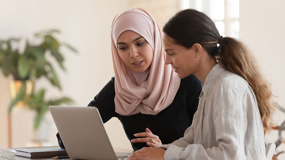 two women working at a laptop