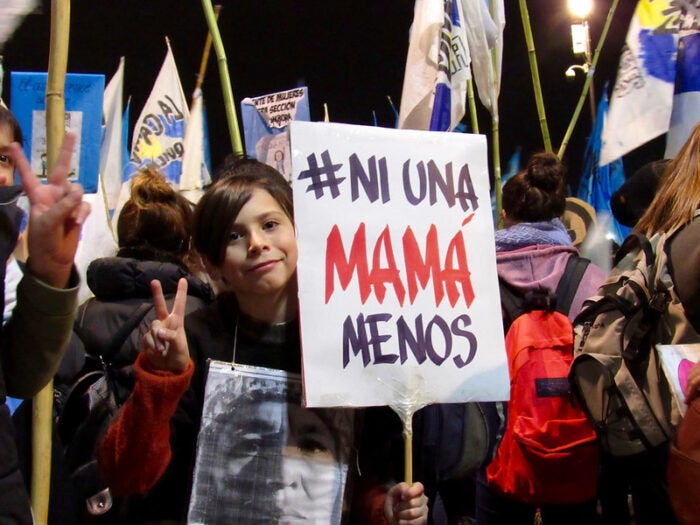 Photo of a young person holding a sign that reads "Ni una Mama menos" at a protest in Buenos Aires, Argentina.