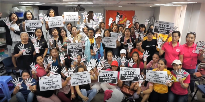 A group of women in Honk Kong hold signs that read "stop gender-based violence at work"