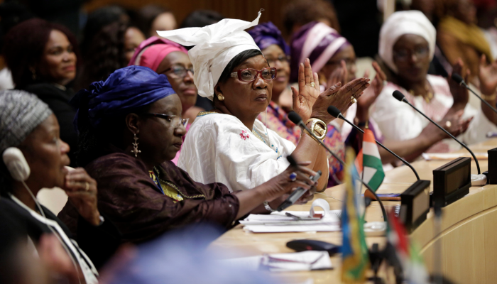 A photo of women participating in a formal peace process echoes the theme of the event.