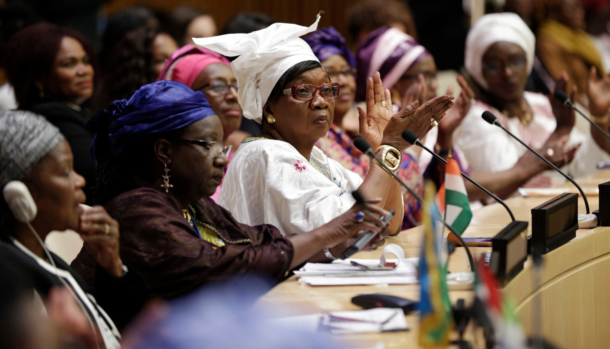 A photo of women participating in a formal peace process echoes the theme of the event.