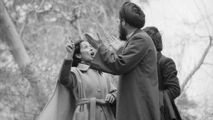 An image of a woman wearing modern clothing speaking with a man during the Iranian Revolution is included to give a visual representation of how women advocated for their rights at the time.